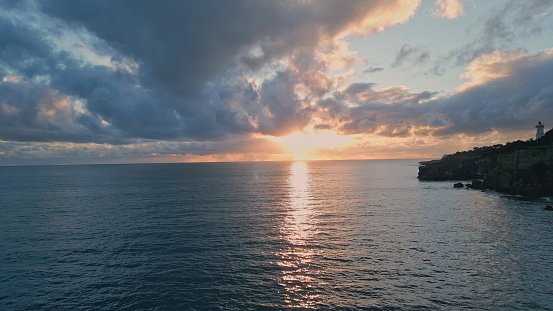 Sunset mountain hill silhouette sea coastline. Bright sunlight breaking clouds