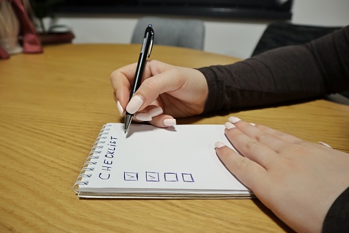 Woman hands writing a checklist on a piece of paper
