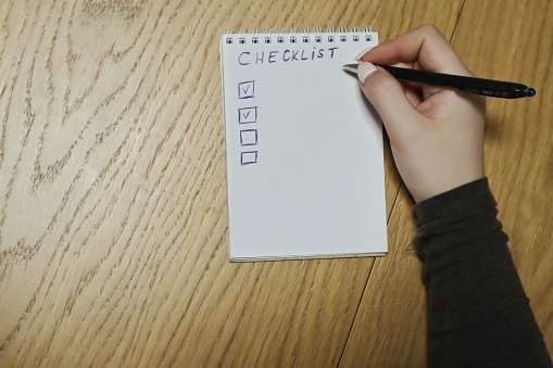 Woman hands writing a checklist on a piece of paper