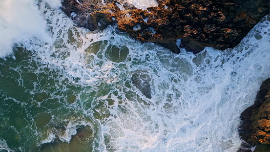 Powerful ocean waves crashing coastal rocks closeup. Rough sea water splashing