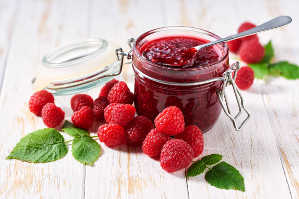istock Spoon with delicious raspberry  marmalade or jam over jar on table. Space for text. 1802986331