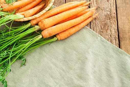 Bunch of fresh carrots with green leaves on rustic wooden background