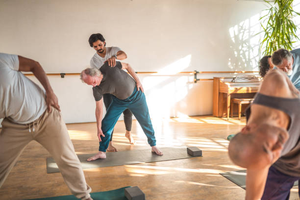 aktive senioren: eine gemischtrassige yogagruppe, die für eine gute gesundheit übt - 16025 stock-fotos und bilder
