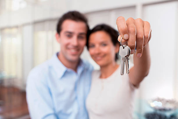 Happy smiling young couple showing keys of their new house stock photo