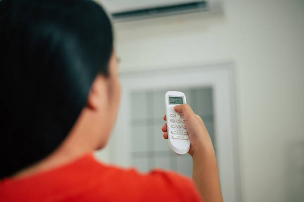 istock Young woman use remote control with air conditioner, Smart Devices at home 1803024175
