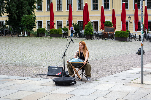 Dresden, Germany, August 4. A street musician girl plays a special electronic musical instrument on a cobblestone square in the city of Dresden on August 4, 2023.