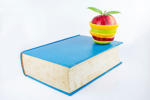 book and an fruits on a white background