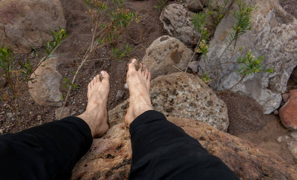 istock Barefoot and muddy man resting on a rock in the mountain 1803093956