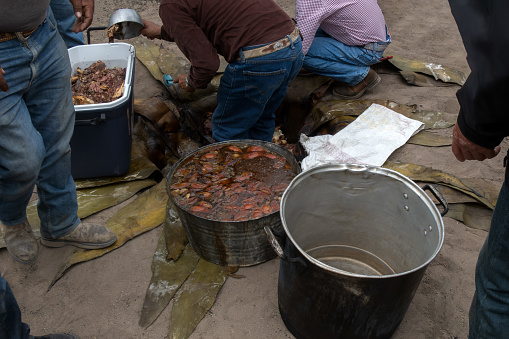 A Men taking beef barbecue from the oven made in the dream in Mexico using maguey leaves