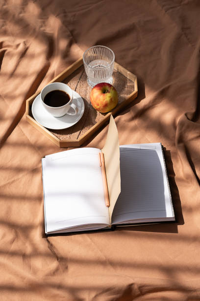 istock Open empty notebook and coffee cup on bed. Cozy morning at home. 1803096077