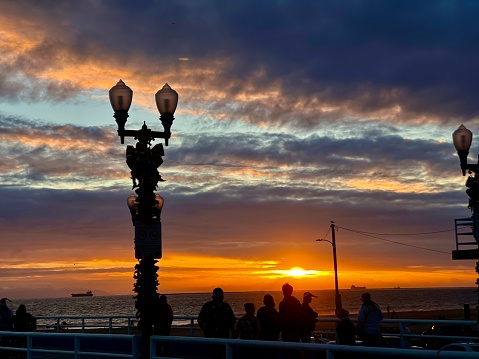 A landscape image of a lamppost on the Seal Beach Pier during sunset.