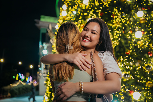 Two young women hug each other when they meet in the city after being apart for a while.