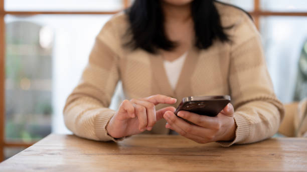 istock A woman using her smartphone while sitting at a table indoors. People and technology concepts 1803162550
