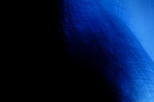 Dark underwater image texture that brightly appears as if blue fabric is softly floating on a black background.