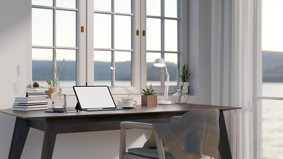 Minimal cozy home office space with blank screen mock up tablet on dark wooden table, large window with sea view. 3d rendering, 3d illustration