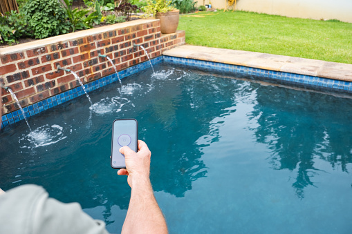 A man uses his mobile phone to turn the pool pump on