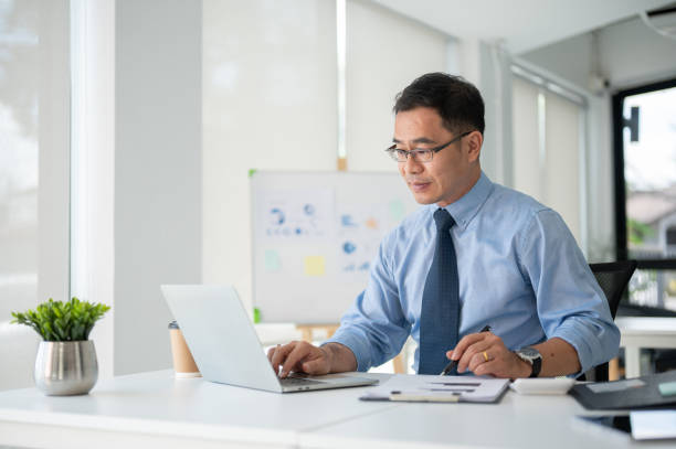 istock Experienced senior businessman working on his project in his office room. Using laptop computer. 1803273999