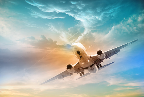 A commercial jet plane flies above dramatic clouds in the light of a beautiful sunset. Travel concept. Cream colored clouds .The concept of travel, rapid transportation, tourism and companies