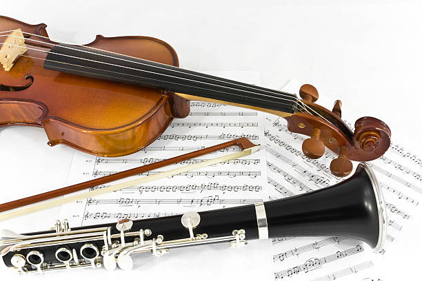 Violin and Clarinet instrument on sheet music Two musical instrument for classical music, a violin part with his bow and a clarinet bottom part. Isolated on white background with printed sheet music. chamber orchestra stock pictures, royalty-free photos & images