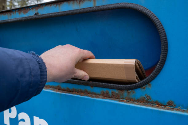 istock Hand throw a cardboard at blue paper container 1803308940