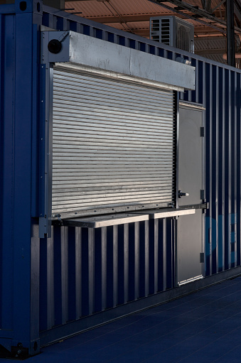 shuttered concession stand (ticket booth) closed for the season, metal gate lowered (shipping container construction) shutters