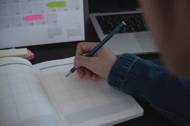 istock Event planner timetable agenda plan on year 2024 schedule event. Business woman checking timetable, taking note on calendar planner notebook on office table. Calendar event plan, work planning, mockup 1803344030