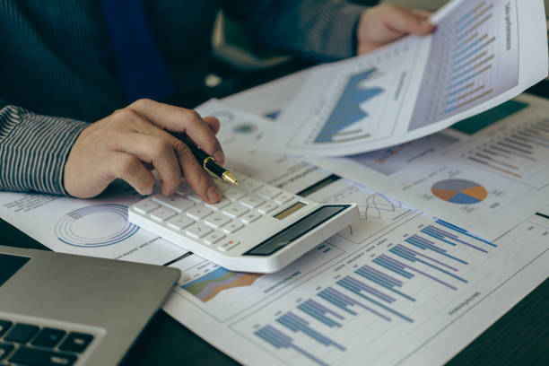 istock Accountant counting on calculator and holding documents in hand close-up Accounting concept with laptop to do math finance on table, analytical research concept 1803378520