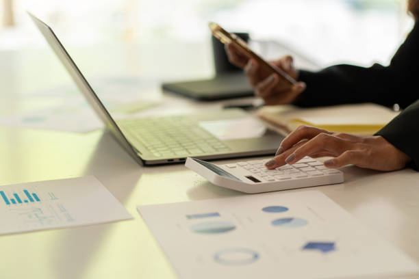 istock Accountant counting on calculator and holding documents in hand close-up Accounting concept with laptop to do math finance on table, analytical research concept 1803379051