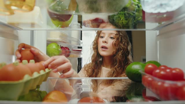 Young Woman Opening Fridge with Fresh Food of Fruits and Vegetables and Taking Ingredients to Eat. Kitchen Refrigerator of Healthy Lady Cooking Evening Meal. POV Freezer Filled with Convenience Supply