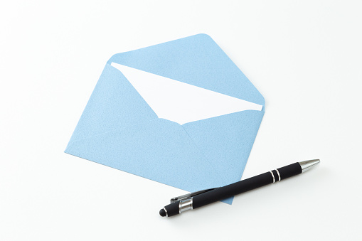 Envelope with blank paper card and pen on white wooden table, flat lay