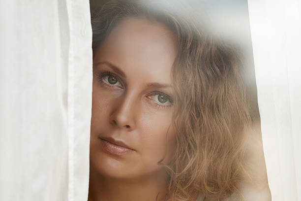 istock Sad beautiful woman looking through the window 180342485