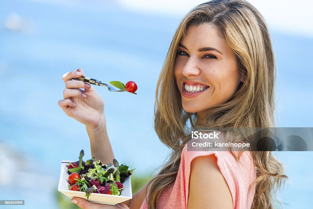 Beautiful woman holding freah salad. Portrait of beautiful young woman holding green salad outdoors at seaside. Beach Stock Photo