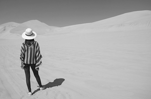 Monochrome image of woman in hat relaxing on the vast Huacachina desert, Ica region, Peru, South America, ( Self Portrait )