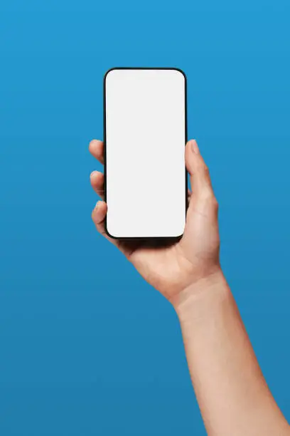 Close-up of a woman's hand holding iPhone and showing blank screen on blue background.
