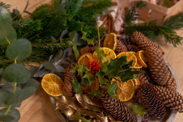istock On wooden table in bowl are dried oranges, pine cones, tools for creating Christmas wreath 1803452647