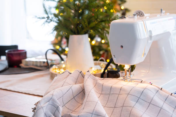 istock Sewing process on a sewing machine, a needle with a thread and a holder close-up stitch the white checkered fabric. Preparation for Christmas and new year, textiles for cozy in festive decor interior 1803471754