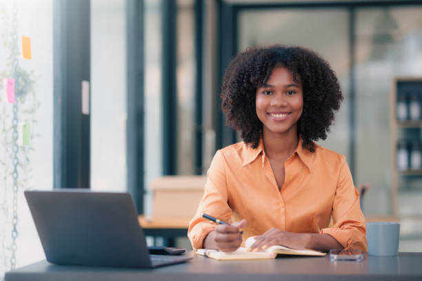 istock Young african american businesswoman using laptop computer, taking notes, working project in modern office. Financier working with documents at workplace. 1803472279