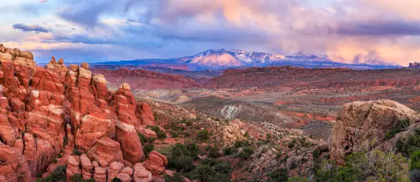 The Las Sal Mountains partially obscured by storm clouds seen from the Fiery Furnace Overlook in Arches National Park, Moab, Utah.