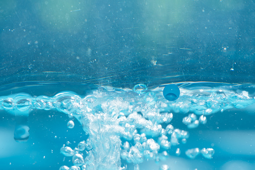 Blue water with ripples on the surface. Defocus blurred transparent white-black colored clear calm water surface texture with splash and bubbles. Water waves with shining pattern texture background.