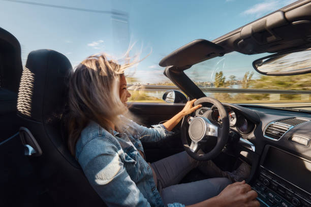 istock Young happy woman enjoying while driving a convertible car. 1803512043