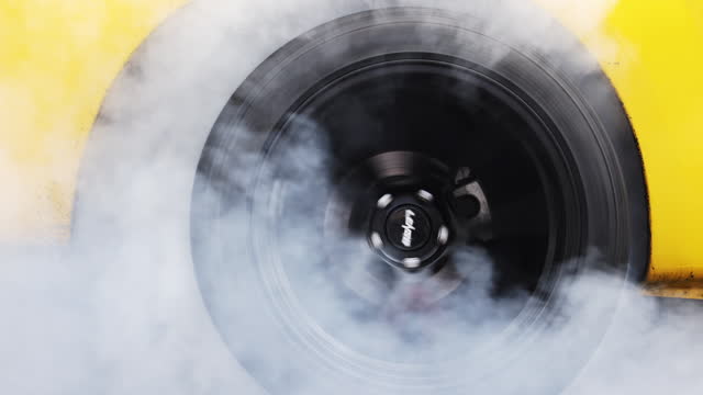 Drag car burning tire, Warm up tire before competition, Drag car wheel, Spinning wheel and smoke, Drag racing car burns rubber tires preparation for race.