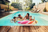 Cheerful family having fun during summer day in the pool.