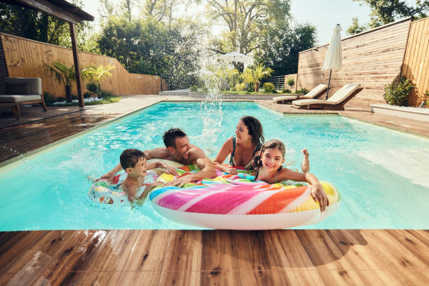 Família alegre se divertindo durante o dia de verão na piscina. - foto de acervo