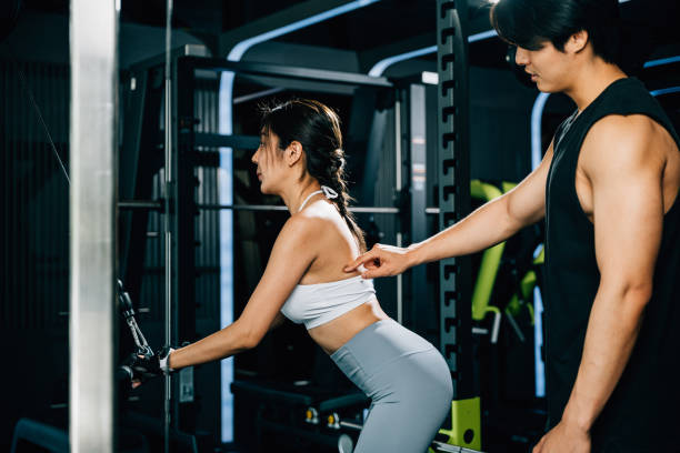 istock Male fitness coach teaching a woman how to use a pulldown cable machine 1803527761