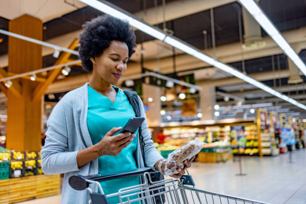 istock Medical practitioner using smart phone while buying groceries in supermarket 1803536444