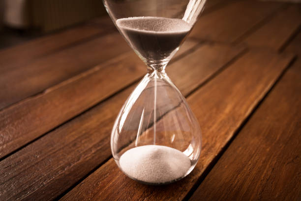 istock Hourglass containing white sand on a rustic wooden board 1803545776