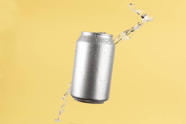 istock Aluminium beer or soda drinking can with water splash on light yellow background 1803556540