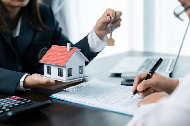 istock Discussion with a real estate agent, House model with agent and customer discussing for the contract to buy, get insurance or loan real estate or property. approved mortgage application form. 1803564162