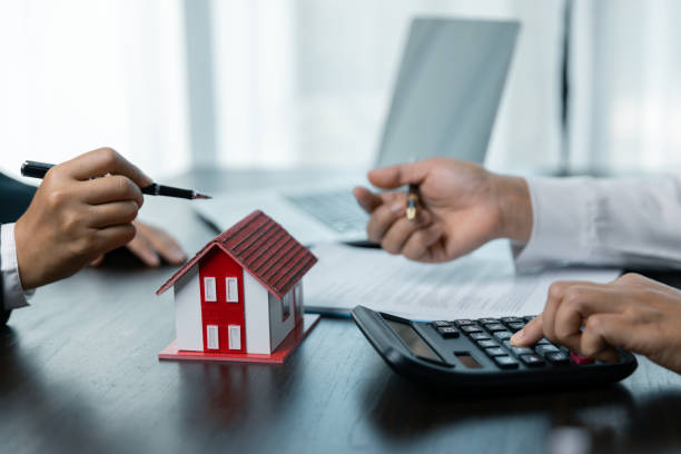 istock Discussion with a real estate agent, House model with agent and customer discussing for the contract to buy, get insurance or loan real estate or property. approved mortgage application form. 1803564163