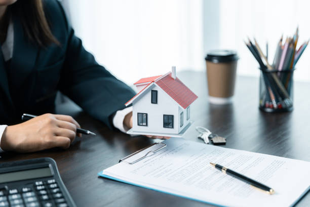 istock Discussion with a real estate agent, House model with agent and customer discussing for the contract to buy, get insurance or loan real estate or property. approved mortgage application form. 1803564166